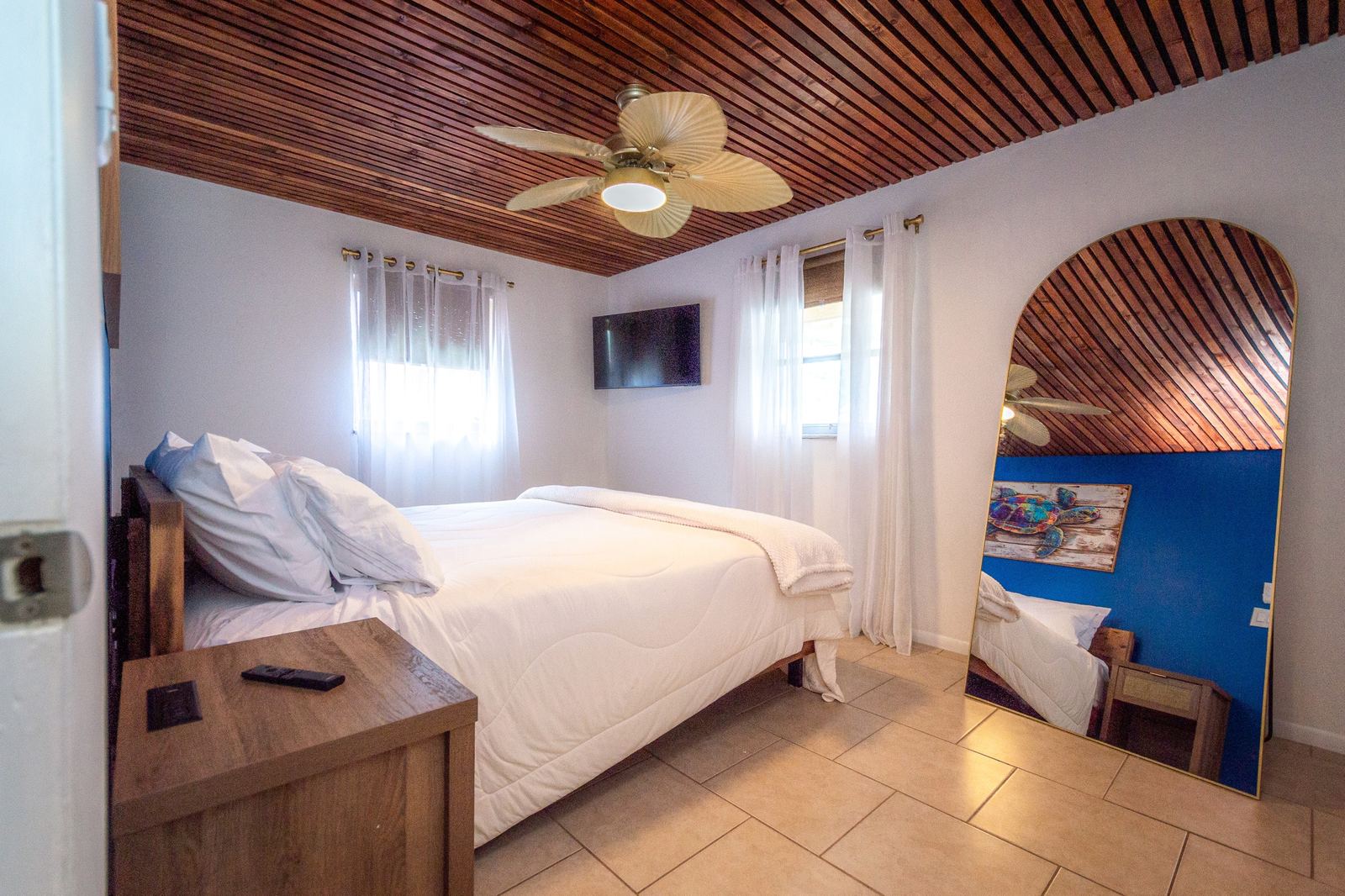 King bedroom with cedar slat ceiling and palm-leaf ceiling fan