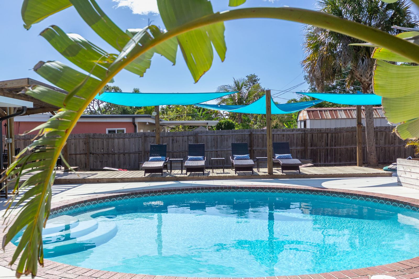 Saltwater pool with turquoise shade sails and four loungers
